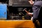 An angry male mechanic is repairing the engine of an old truck with an open hood hitting it with a hammer