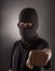 Angry man in a balaclava on a dark background. Rebellious protester in a mask shows his fist