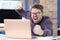 Angry man with glasses waves his fist at laptop monitor