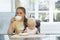 Angry mom holds the baby in her arms and drinks coffee. Mother and lack of time