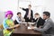 Angry multiethnic businesspeople with colleague in pink wig at meeting