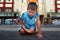 Angry offended child sits on the ground in the street and looks with an angry look.