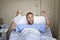 Angry patient man at hospital room lying in bed pressing nurse call button holding potty