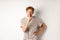 Angry redhead man looking displeased and hushing at camera, making shh gesture, standing over white background