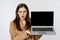 Angry and shocked saleswoman showing laptop screen, frowning and staring offended, standing over white background