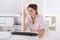 Angry and shocked young woman sitting in the office wearing rose