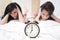 Angry sleeping women looking at a ringing clock