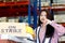 Angry unhappy young Asian woman wearing safety vest, holding helmet and giving thumb down standing with strike banner placard sign