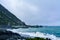 Angry waves breaking onto black sand beach of a small bay. A stormy day on the coastline of Cape Palliser near