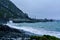 Angry waves breaking onto black sand beach of a small bay. A stormy day on the coastline of Cape Palliser near