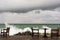 Angry waves crash over rocks on the coast near abandoned tables