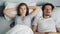 Angry wife covering face with pillow while sleeping husband snoring in bed