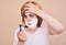 Angry woman with shaving foam on her face holding and looking at a razor