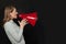 Angry woman shouting with loudspeaker megaphone on black background
