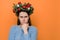 Angry woman in traditional Christmas wreath looking at camera with gloomy sad expression, feeling insulted or offended