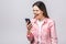 Angry young beautiful woman in casual shouting on smartphone over white background