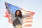 Angry young black woman screaming holding United States of America flag outdoor.
