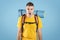 Angry young traveler with rucksack screaming on blue studio background