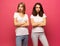 Angry young two ladies standing over pink background