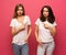 Angry young two ladies standing over pink background