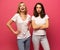 Angry young two ladies standing over pink background