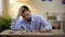 Angry young unemployed man sitting at table, counting savings, financial crisis