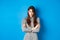 Angry young woman in dress feel unfair, cross arms on chest and frowning offended, standing on blue background