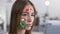 Animated red hearts on the eyes of young attractive woman with painted social media icons on her face. Caucasian girl