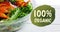 Animation of 100 percent organix text in green over fresh organic vegetable salad in bowl on wood