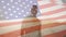Animation of american flag waving over african american man standing on beach