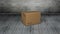 Animation of cardboard box falling on grey wooden floor with grey bricks in background