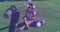 Animation of floating purple shapes over woman sitting on grass reading book in park