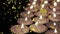 Animation of gold confetti falling over lit tea light candles on black background