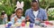 Animation of happy african american father and son painting easter eggs in garden