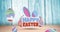 Animation of happy easter text with easter bunny ears and easter eggs on blue wooden surface