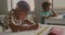 Animation of letters floating over bust african american schoolboy writing at desk in class