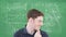 Animation of mathematical equations on green board over caucasian man scratching chin