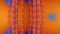 Animation of orange patterned strips over grid of blue pixels changing size on orange background