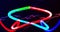 Animation of red and blue electrical currents over colourful neon light trails on black