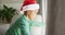 Animation of sad african american boy wearing santa hat looking outside window at christmas time