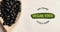 Animation of vegan food text in green over fresh organic black beans in wooden bowl