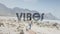 Animation of the word vibes in black over woman walking on beach