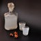 Anise liqueur, strong alcohol in a glass decanter and two glasses on a black background next to spices