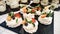 Anna Pavlova desserts on a black plate and jars of tirramissu on background