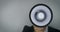 Announcement - businessman with megaphone in front of face on gray background