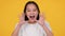 Announcement. Studio portrait of little asian girl shouting out loudly, holding hands near mouth like megaphone