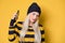 Annoyed girl on the phone, model wearing woolen cap and sweater, isolated on yellow background. Annoying woman talking. Nuisance