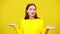 Annoyed irritated young woman gesturing in slowmo and looking at camera at yellow background. Portrait of sarcastic