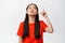 Annoyed teen asian girl pointing and looking up with tired, fed up face expression, being pissed off, standing in red t