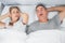 Annoyed wife blocking her ears from noise of husband snoring